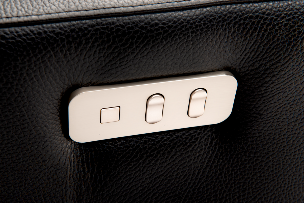 Nahaufnahme der Bedienelemente eines Relaxsessels aus schwarzem Leder mit silbernen Knöpfen.