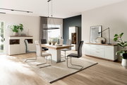 Moderne Esszimmermöbel mit Esstisch, Stühlen, Sideboard und Highboard in einem hellen Raum mit Holzboden, seitliche Perspektive.
