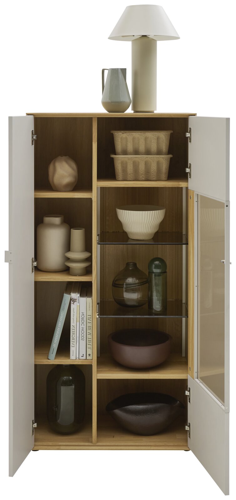 Offener, moderner Holzschrank mit weißen Türen und Glasfach, frontal in Augenhöhe fotografiert; innen mit Deko-Vasen, Schalen, Büchern und Körben, oben mit Tischlampe und Krug.
