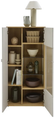 Offener, moderner Holzschrank mit weißen Türen und Glasfach, frontal in Augenhöhe fotografiert; innen mit Deko-Vasen, Schalen, Büchern und Körben, oben mit Tischlampe und Krug.
