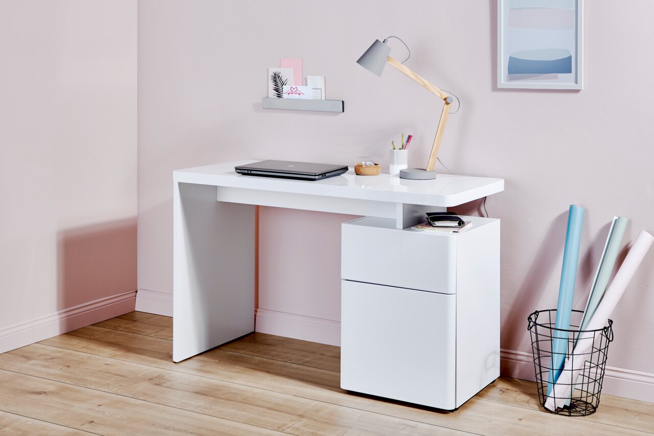 Moderner weißer Schreibtisch mit Schubladenelement, seitliche Perspektive, dekoriert mit Lampe, Laptop und Schreibutensilien.