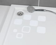 Blick von oben auf eine Duschwanne mit weißen, eckigen Anti-Rutschstickern und einer Handbrause.
