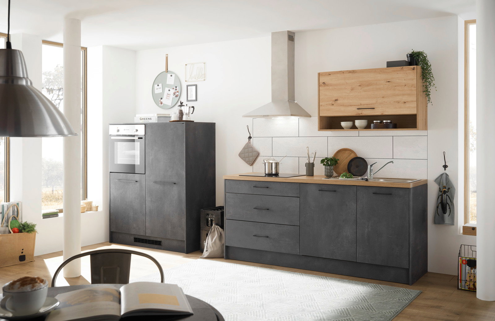 Moderne Küchenzeile in dunklem Grau mit Holzarbeitsplatte, bestehend aus einem Hochschrank mit integriertem Backofen und einer Arbeitsfläche mit Spüle und Kochfeld. Perspektive von vorne.