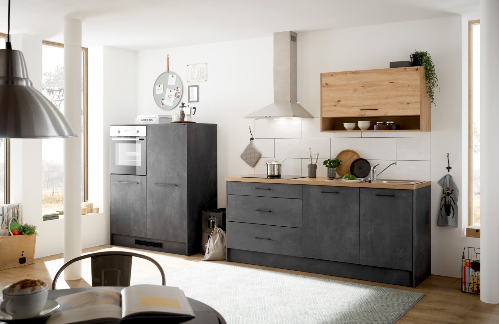 Moderne Küchenzeile in dunklem Grau mit Holzarbeitsplatte, bestehend aus einem Hochschrank mit integriertem Backofen und einer Arbeitsfläche mit Spüle und Kochfeld. Perspektive von vorne.