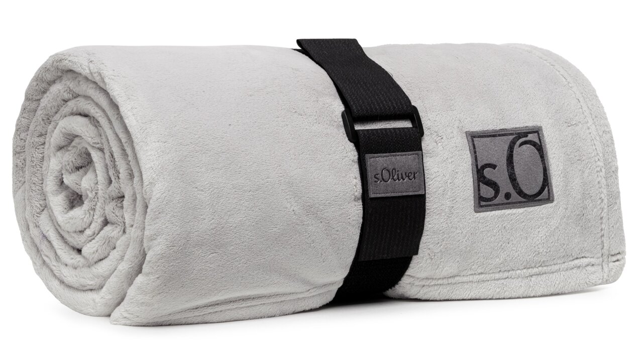 Graue, zusammengerollte Kuscheldecke von s.Oliver mit schwarzem Tragegurt, seitliche Perspektive
