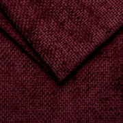 Close-up van een wijnrode, gestructureerde stof die wordt gebruikt voor een gestoffeerd bedframe.