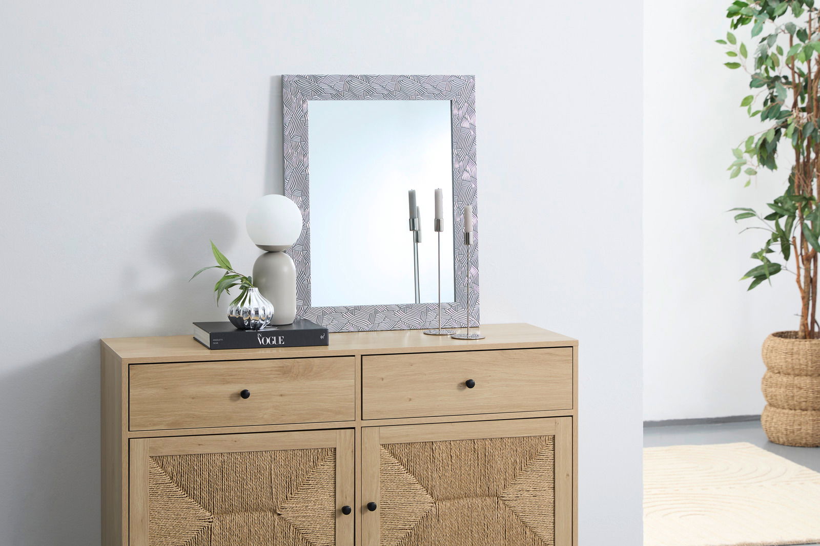 Spiegel FINN mit dekorativem Rahmen, auf einer Kommode stehend, frontal fotografiert.