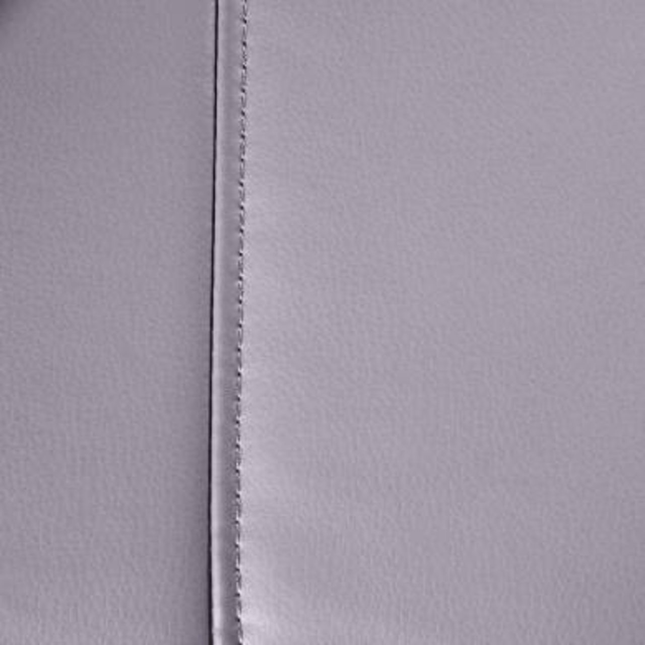 Nahaufnahme der grauen Lederoberfläche eines Massagesessels mit sichtbarer Naht.