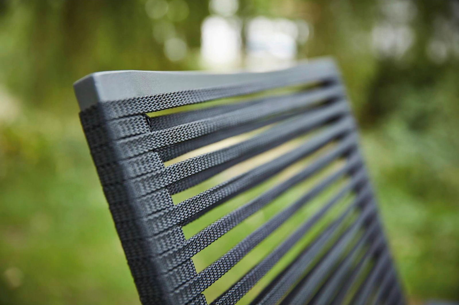 Nahaufnahme der Rückenlehne eines Sessels mit grauen, gewebten Streifen, im Freien fotografiert.