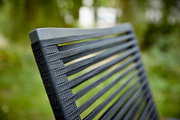 Nahaufnahme der Rückenlehne eines Sessels mit grauen, gewebten Streifen, im Freien fotografiert.