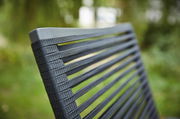 Nahaufnahme der Rückenlehne eines Sessels mit grauen, gewebten Streifen, im Freien fotografiert.