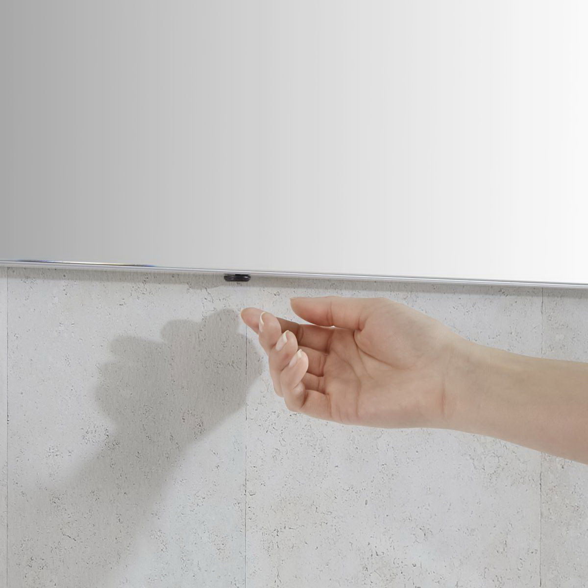 Nahaufnahme einer Hand, die sich einem Sensor unter einem Badezimmerspiegel nähert.