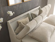 Nahaufnahme eines Boxspringbetts mit beigem Kopfteil und Kissen, seitliche Perspektive