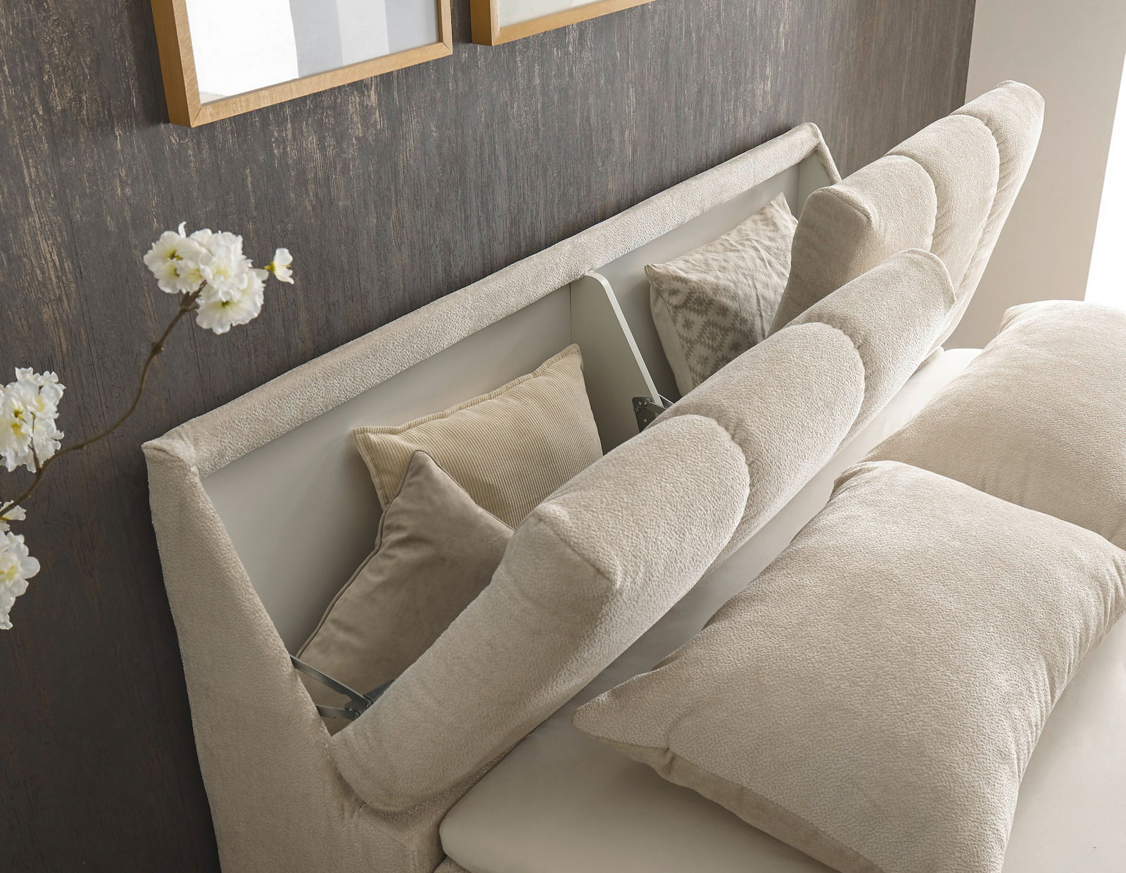 Nahaufnahme eines Boxspringbetts mit beigem Kopfteil und Kissen, seitliche Perspektive