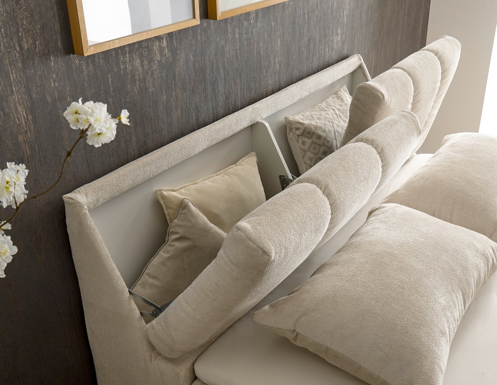 Nahaufnahme eines Boxspringbetts mit beigem Kopfteil und Kissen, seitliche Perspektive