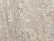 Nahaufnahme eines Designer-Teppichs mit detailliertem Muster in Beige- und Grautönen, aus seitlicher Perspektive aufgenommen.