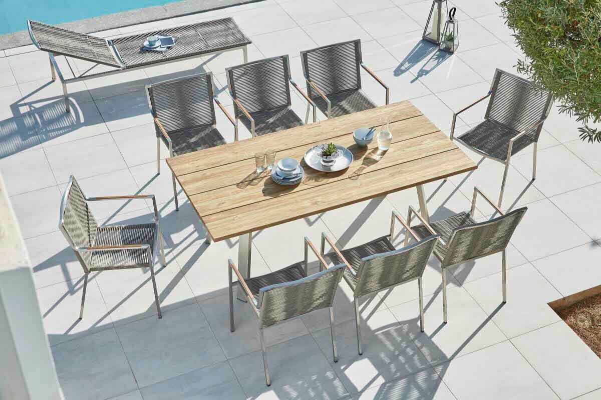 Gartentisch mit Holzplatte und acht Stühlen, aus der Vogelperspektive fotografiert, auf einer Terrasse neben einem Pool.