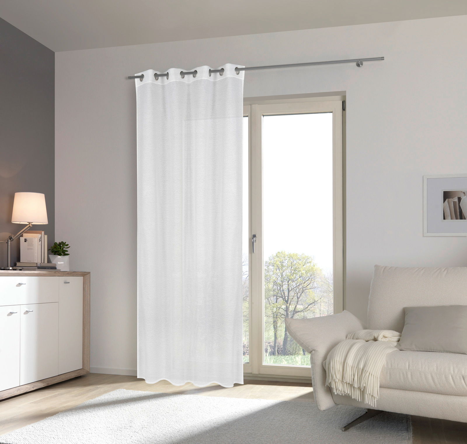 Weißer Ösenschal 135x245cm vor einem Fenster in einem modernen Wohnzimmer, seitliche Perspektive