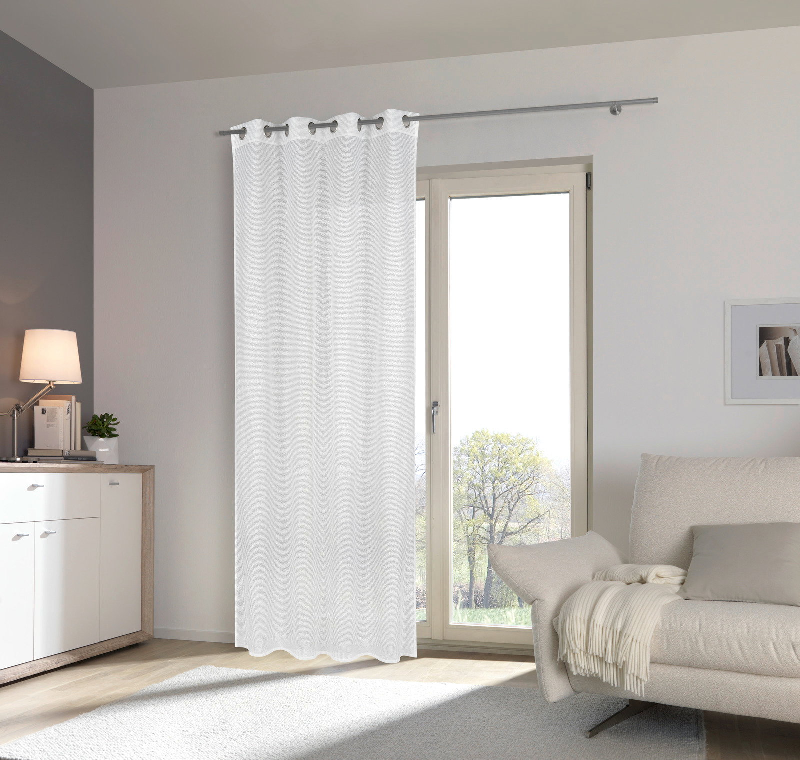 Weißer Ösenschal 135x245cm vor einem Fenster in einem modernen Wohnzimmer, seitliche Perspektive