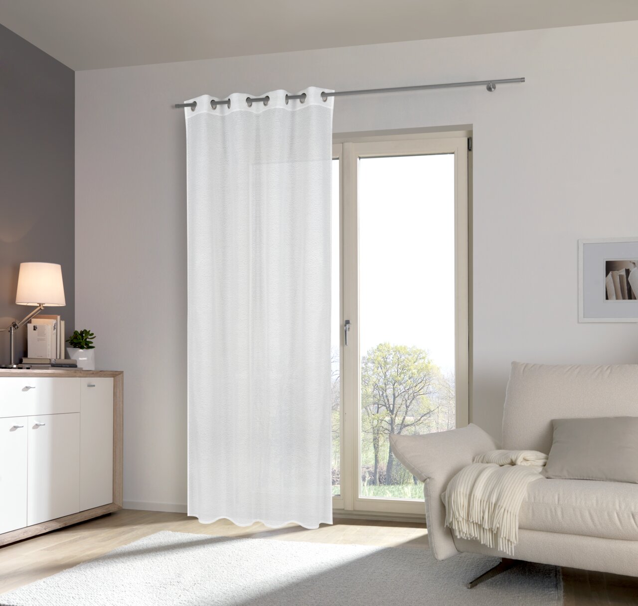 Weißer Ösenschal 135x245cm vor einem Fenster in einem modernen Wohnzimmer, seitliche Perspektive
