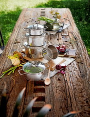 Topfset Alicante 5-tlg aus Edelstahl auf einem rustikalen Holztisch, fotografiert aus der Vogelperspektive, umgeben von frischen Zutaten und Küchenutensilien.