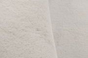 Nahaufnahme eines weißen Fellteppichs aus seitlicher Perspektive.