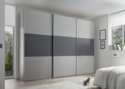 Moderner Schwebetürenschrank in Grau mit drei Türen, seitliche Perspektive im Schlafzimmer.