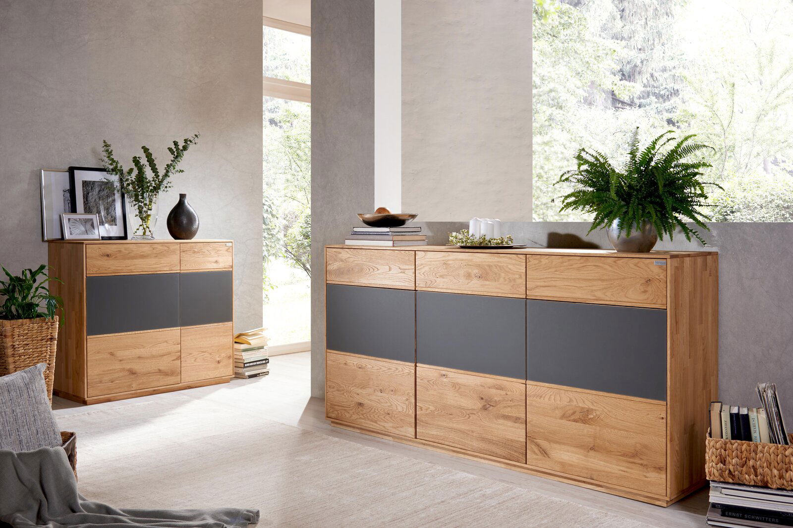 Zwei moderne Kommoden aus Holz mit grauen Akzenten, dekoriert mit Pflanzen und Büchern, in einem hellen Raum mit Blick auf ein Fenster.