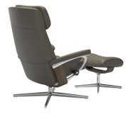 Achterkant van een moderne fauteuil met voetenbankje, uitgevoerd in donkergrijs leer en met een metalen frame.