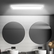 LED-Deckenleuchte mit Bewegungssensor, rechteckig, an der Decke eines modernen Badezimmers mit zwei runden Spiegeln montiert, seitliche Perspektive.