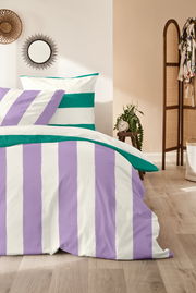 Bettwäsche-Set mit lila und grünen Streifen, fotografiert aus einer seitlichen Perspektive in einem gemütlichen Schlafzimmer.
