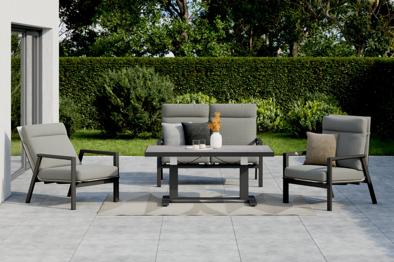 Amatio Pro Gartenbank 2-Sitzer LUZERN PLUS Gartenmöbel-Set mit zwei grauen Sesseln, einer grauen Gartenbank und einem Tisch auf einer Terrasse, umgeben von grüner Hecke und Bäumen, aus frontaler Perspektive.