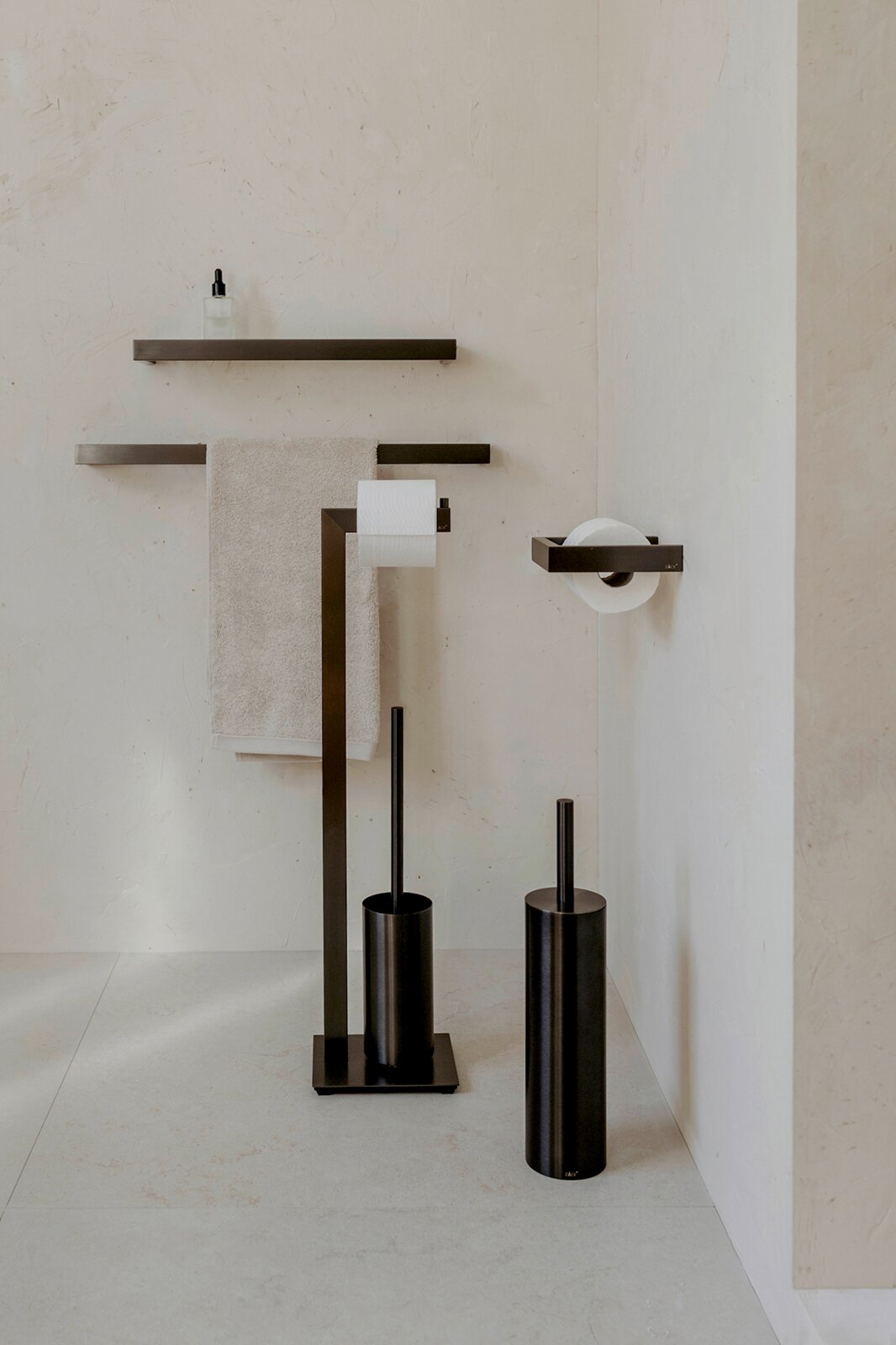Modernes Badezimmer-Accessoire-Set in mattschwarz mit Handtuchhalter, Wandregal, Toilettenpapierhalter und WC-Bürstengarnitur, frontal in leichter Seitenperspektive aufgenommen