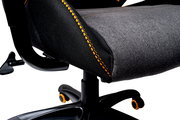 Nahaufnahme eines Gaming-Stuhlsitzes mit grauem Stoff und orangefarbenen Nähten, seitliche Perspektive