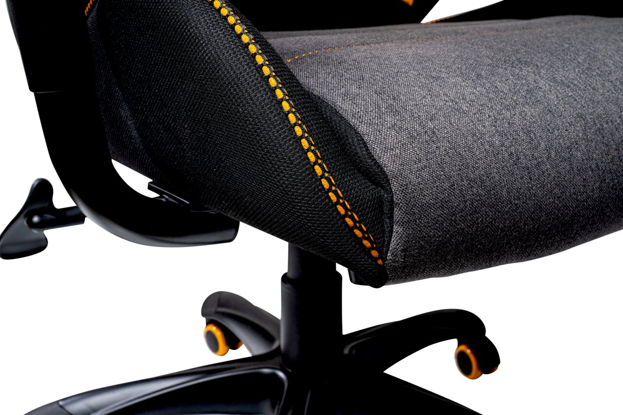 Close-up van de zitting van een gamingstoel met grijze bekleding en oranje stiksels, gezien vanaf de zijkant