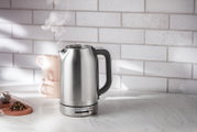 Moderner Edelstahl-Wasserkocher mit 1,7 Liter Fassungsvermögen, seitliche Ansicht, auf einer Küchenarbeitsplatte mit Tassen und Tee.