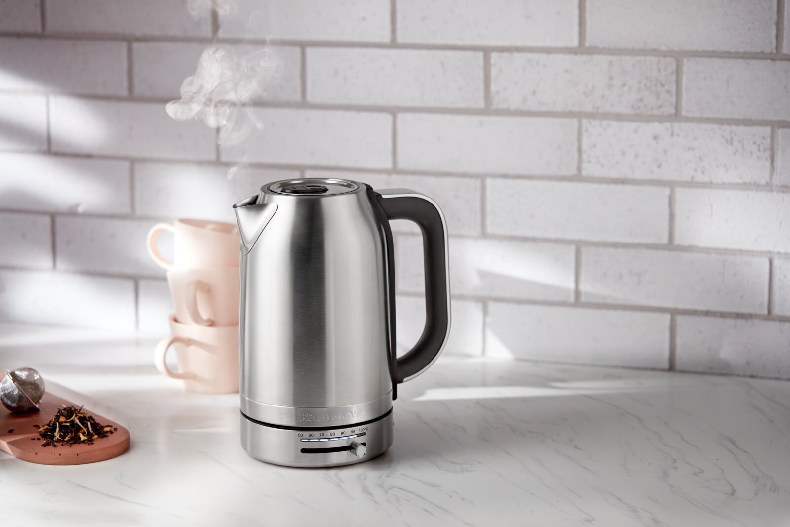 KitchenAid Wasserkocher 1,7l 5KEK1701ESX Moderner Edelstahl-Wasserkocher mit 1,7 Liter Fassungsvermögen, seitliche Ansicht, auf einer Küchenarbeitsplatte mit Tassen und Tee.