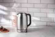 Moderner Edelstahl-Wasserkocher mit 1,7 Liter Fassungsvermögen, seitliche Ansicht, auf einer Küchenarbeitsplatte mit Tassen und Tee.