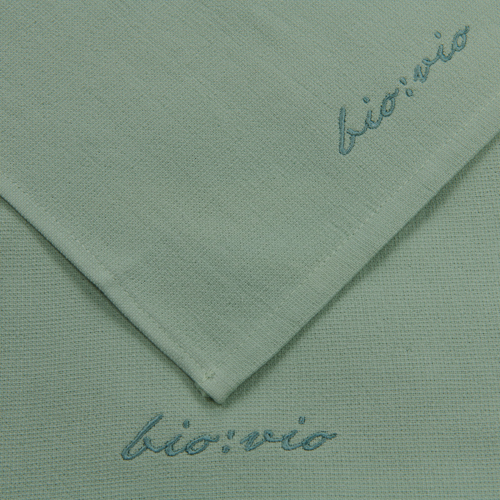 Zwei grüne Gästetücher mit der Aufschrift 'bio:vio', aus der Vogelperspektive fotografiert.