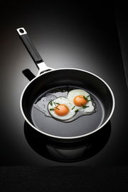 Bratpfanne mit einem Durchmesser von 20 cm, von oben fotografiert, mit zwei Spiegeleiern und Schnittlauch garniert.