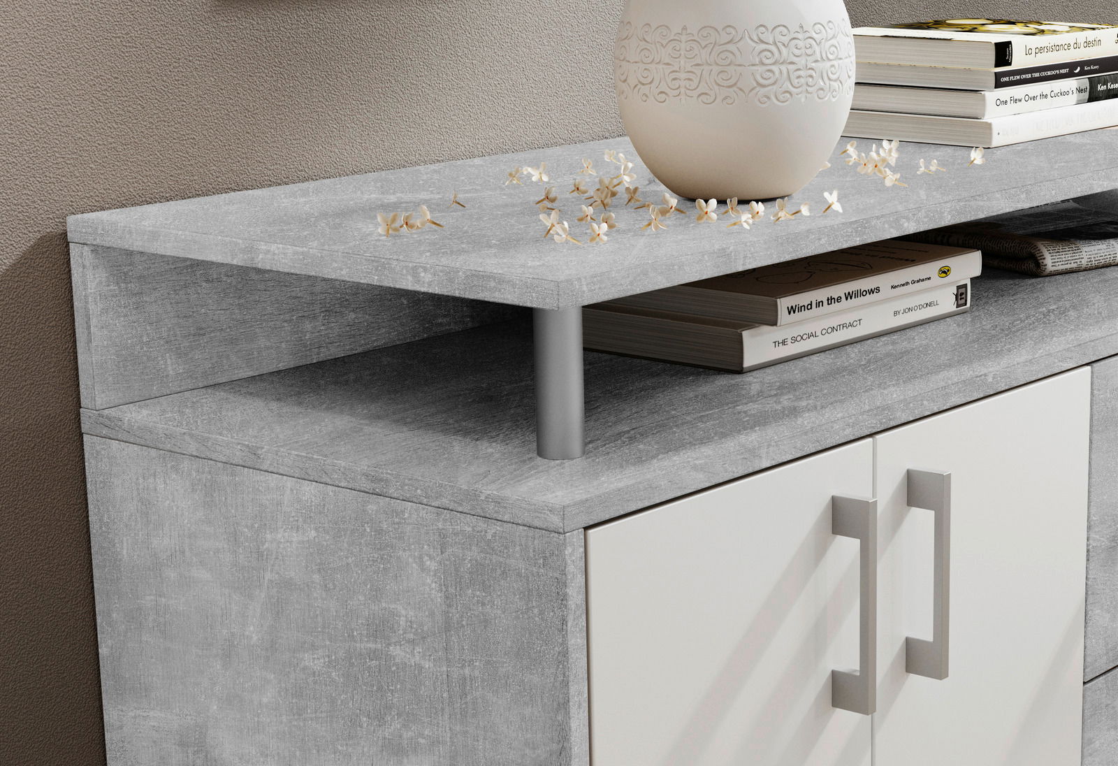 Nahaufnahme eines modernen Sideboards mit grauer Steinoptik-Oberfläche, dekoriert mit einem weißen Keramikgefäß und Büchern, aus seitlicher Perspektive.