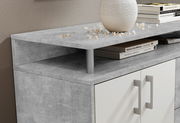 Nahaufnahme eines modernen Sideboards mit grauer Steinoptik-Oberfläche, dekoriert mit einem weißen Keramikgefäß und Büchern, aus seitlicher Perspektive.