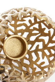 Goldener Teelichthalter mit filigranem, durchbrochenem Design, von oben betrachtet.