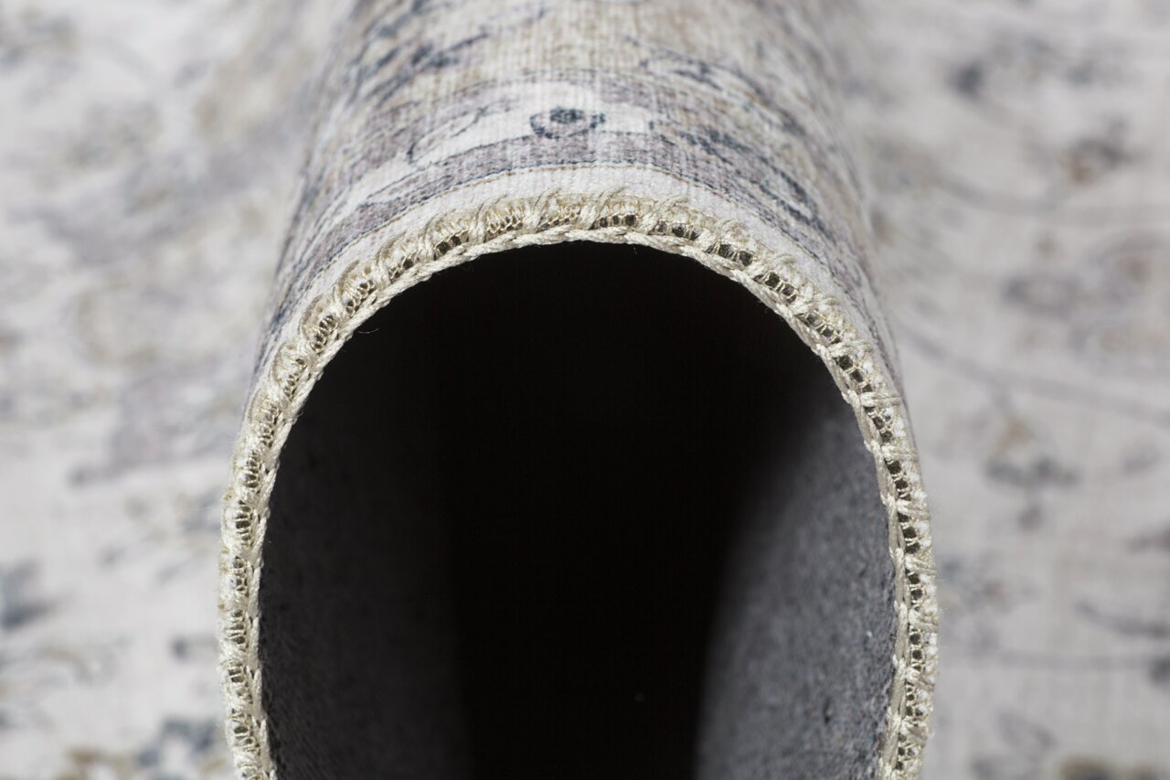 Nahaufnahme eines gerollten Teppichs mit sichtbarer Kante und detaillierter Textur.