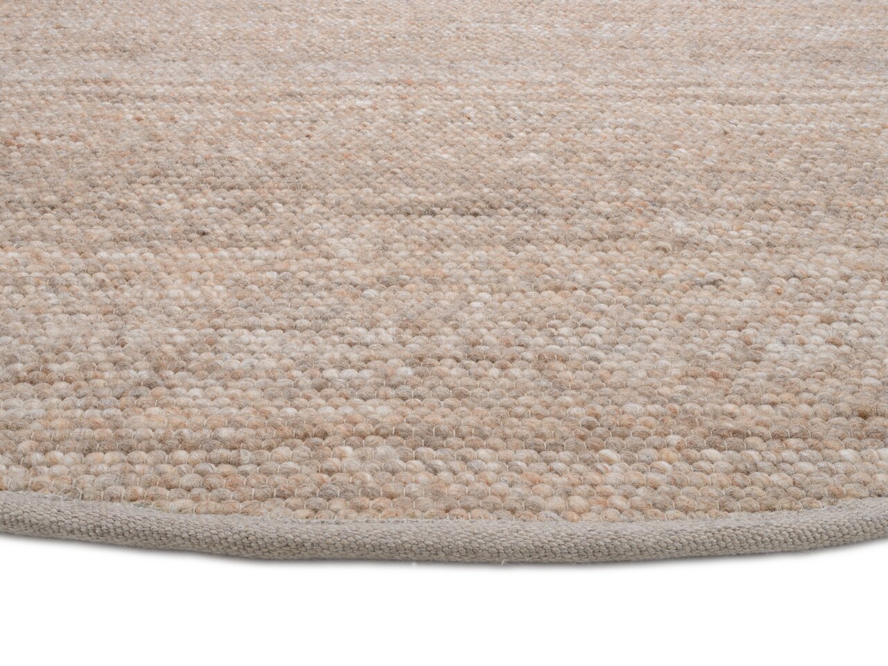 Nahaufnahme eines handgewebten Teppichs in natürlichen Beige- und Brauntönen, von der Seite fotografiert.