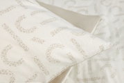 Close-up van beddengoed met een subtiel luipaardpatroon in beige op een witte achtergrond, gefotografeerd vanuit een perspectief van bovenaf.