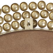 Nahaufnahme eines runden Spiegels mit dekorativem goldenen Rand aus kugelförmigen Elementen, Rückansicht mit Aufhängung.