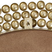 Nahaufnahme eines runden Spiegels mit dekorativem goldenen Rand aus kugelförmigen Elementen, Rückansicht mit Aufhängung.