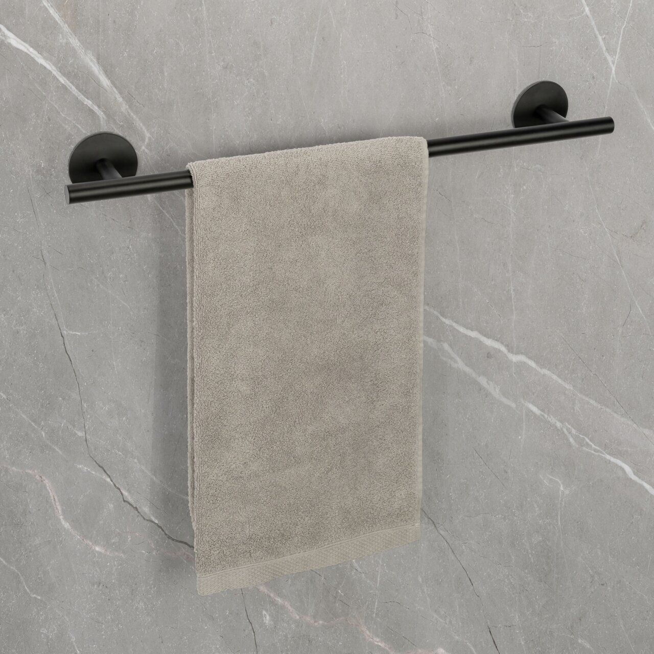 Badetuchstange Uno 60 cm in Schwarz, montiert an einer grauen Wand, mit einem grauen Handtuch. Perspektive: Frontalansicht.