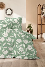 Grüne Bettwäsche mit weißem Blumenmuster in einem gemütlichen Schlafzimmer, seitliche Perspektive